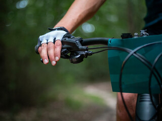 Close-up of cyclist's gloved hand gripping handlebars during outdoor biking activity in natural...