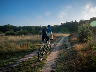 Fototapeta premium Cyclist riding mountain bike on dirt path through countryside landscape during outdoor adventure