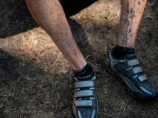Detailed view of muddy cycling shoes and legs after intensive mountain bike trail riding session