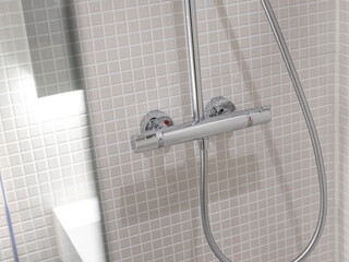 Chrome thermostatic shower mixer valve with temperature controls mounted on white mosaic tile wall