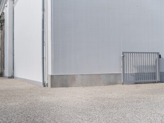 Modern commercial building exterior with corrugated metal siding, concrete base and security gate...