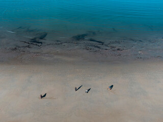 Overhead perspective of people enjoying beach activities on sandy shoreline with clear blue ocean water