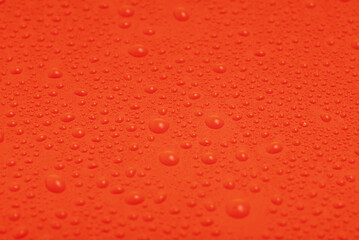 Texture of water drops on red plastic.
