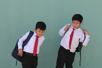 Two dark-skinned Latino boys carry their backpacks and walk back to school to study and learn