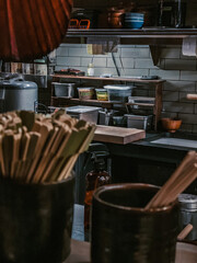 Interior of a Japanese kitchen with shelves of ingredients, rice cooker, and prep table captured in warm evening lighting.