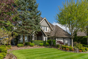 Two story stucco luxury house with nice spring blossom landscape in Vancouver, Canada, North America. Day time on May 2025.