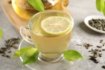 Refreshing green tea with lemon and leaves on light table, closeup