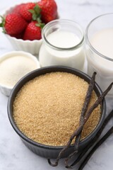 Different ingredients for panna cotta. Milk, sugar, vanilla and strawberries on white marble table, closeup