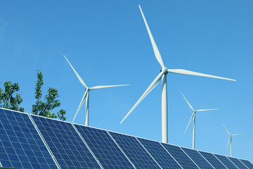 Solar panels and wind turbines against blue sky outdoors. Alternative energy source