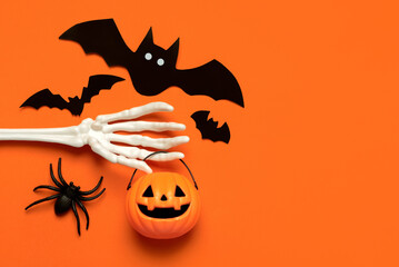Top view of skeleton hand bone with pumpkin basket,bats, spider and space for text. Halloween...