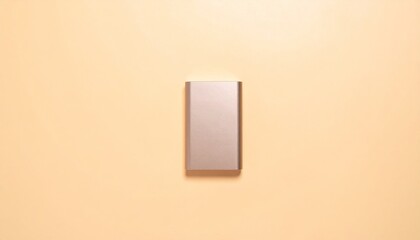 Rectangular Silver Power Bank Centered on Pastel Beige Background Studio Shot