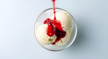Delicious vanilla ice cream scoops topped with vibrant red berry sauce in a glass bowl