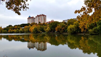 Fototapeta premium Autumn park reflecting buildings on a calm lake