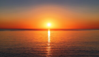 vibrant orange sunset reflected on calm sea with clear sky and setting sun on the horizon