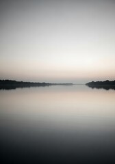 Obraz premium Tranquil lake landscape reflecting dawn's soft light with misty horizons and serene water surface