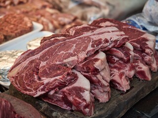 Raw beef steak on a white plate in a restaurant setting. Chef cutting fresh meat before cooking.