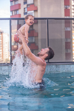 Dad throwing his child up in the pool