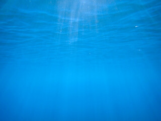 Light filtering down through blue water. Underwater sunlight in deep sea. Sunlight viewed from blue abyss, slow motion. Underwater sunlight shining deep under water with ripples on wave surface. sun.
