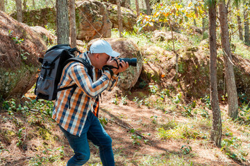 Photographer crouching to capture nature in forest with DSLR camera