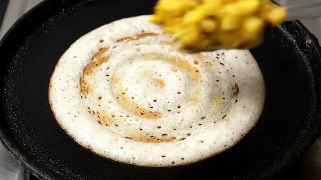Making dosa pouring batter on hot griddle for crispy indian crepe