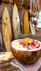 Vibrant Acai Bowl in Coconut Shell with Surfing Background