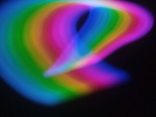 A multicolored abstract by moving strokes of light, creating bright, swirling streaks of rainbow-colored light on a dark background