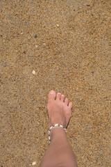Foot stepping onto golden sand at a beach during a sunny day in summer