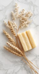 Pale yellow soap bar rests beside beige wheat stalks on a marble surface; minimalist, natural aesthetic