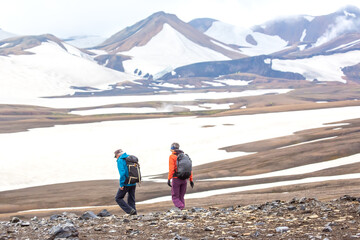 Fototapeta premium Hikers exploring the rugged terrain of Iceland's vast landscapes under a cloudy sky