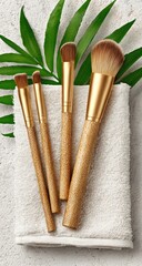Natural makeup brushes on a white towel, next to a palm leaf