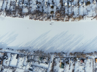 Aerial view of snow-covered houses near frozen river in Uralsk, Kazakhstan, during winter. c.