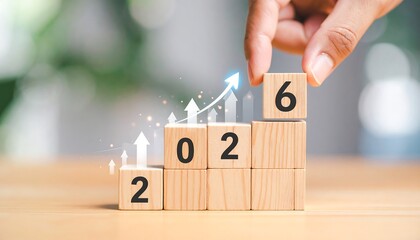 Wooden blocks with the numbers 2, 0, 2, and 6 are stacked in ascending order, with arrows and glowing dots symbolizing growth, as a hand places the final 6 block.