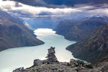 Stacked stones overlook the serene waters of a fjord in Norway's dramatic landscape