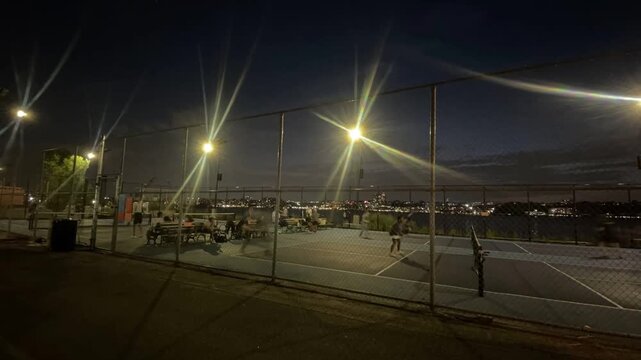 friends play pickleball at night