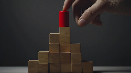Hand Placing Red Cylinder on Wooden Block Pyramid