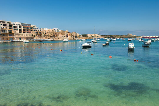 BIRZEBBUGA, MALTA - JUNE 28, 2023: the Colorful small fishing boats moored with buoys in St George's Bay, in Birzebbuga, Malta. This was on a sunny afternoon.

