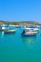 Malta Republic, Malta Island. 28. 06.2023. Marsaxlokk city, The harbour and coloured traditional boats on a hot sunny day.