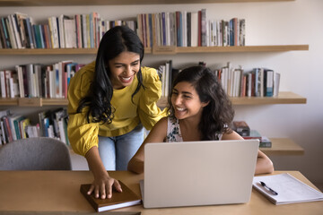 Indian women colleagues laughing at meeting in office, working on joint task or project, share...