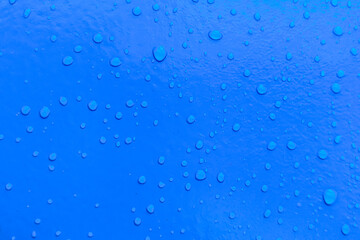 Drops of water on a vibrant blue surface, creating a beautiful and refreshing texture.