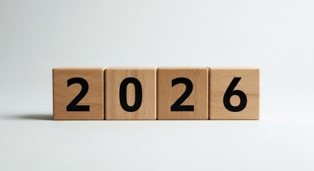 Four light-brown wooden blocks, each with a single black digit, forming the year 2026.  A simple, minimalist representation of the new year