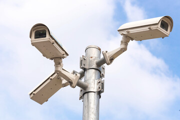 Three security cameras against blue sky
