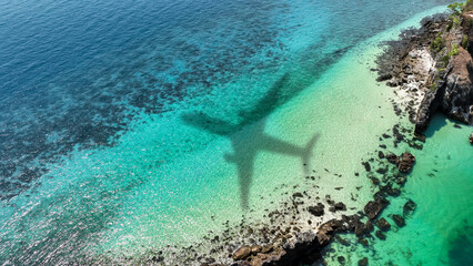 Aerial view of shadow passenger plane silhouette and sandy beach blue sea with waves at sea beach summer vacation sea travel concep
