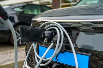 Close-up of an electric vehicle charging at a public station. This image showcases the rise of...