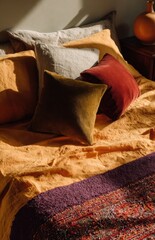 Warm sunlight illuminating cozy bedroom with velvet and linen pillows