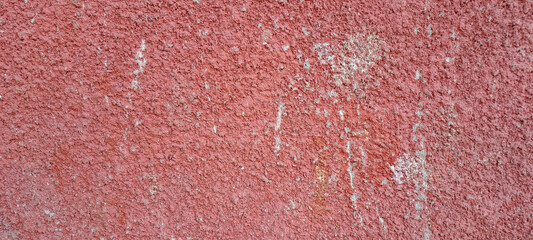 Close-up of an old painted red concrete wall with rough texture, peeling paint, uneven and grungy surface for construction backgrounds.	
