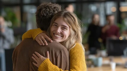 A very amiable girl welcomes a new member of the creative team at a contemporary office by embracing a young man.