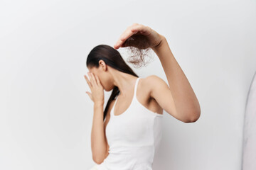 Hair loss concern, beauty struggles, self image issues A woman in a white tank top is seen holding...