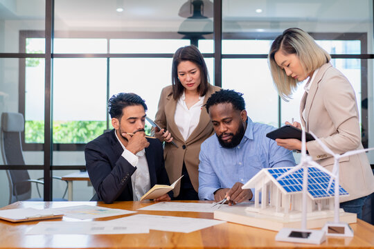 team of multiethnic coworker meeting on solar roof system project with solar panel house model, responsibility of green industry alternative renewable clean environment energy for sustainable business