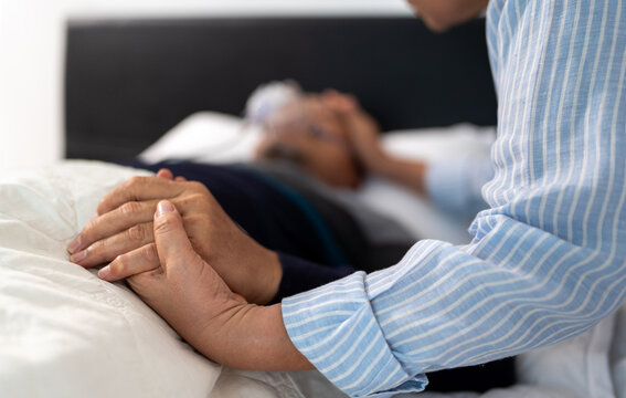 scene of bedridden patient, focus on hand of wife holding hands illness elderly hopeless senior man. home caregiver nurse visit retirement patient for health check up recovery process medical service - Powered by Adobe