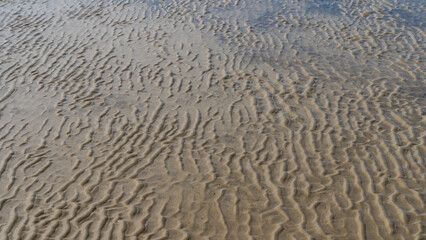 The seabed at low tide. A wavy pattern of sandy ridges and puddles of water. Top view.Close-up. Full screen. Madagascar. Morondava. Mozambique Channel.